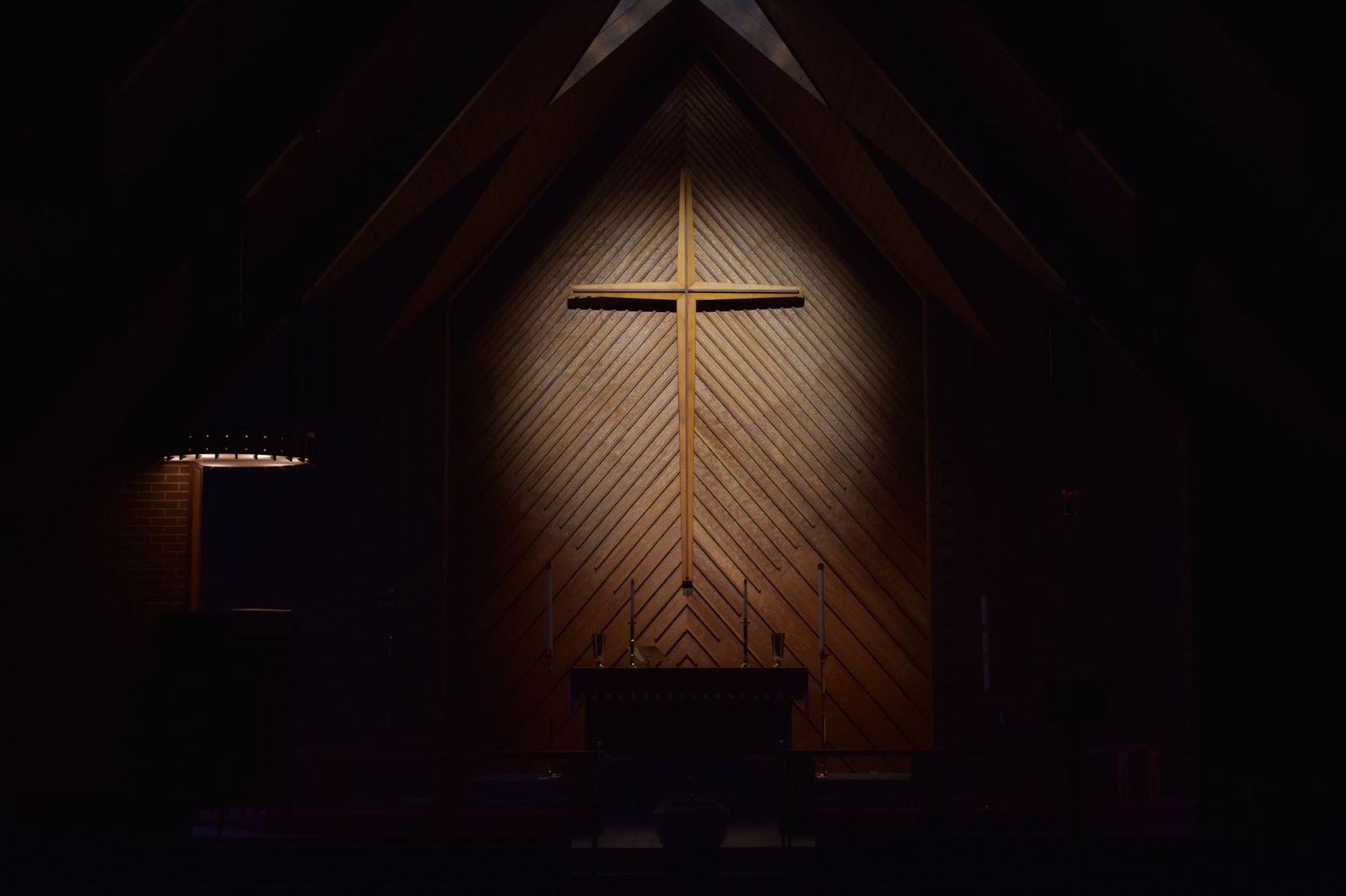 A cross inside of a church, illuminated by a spotlight.