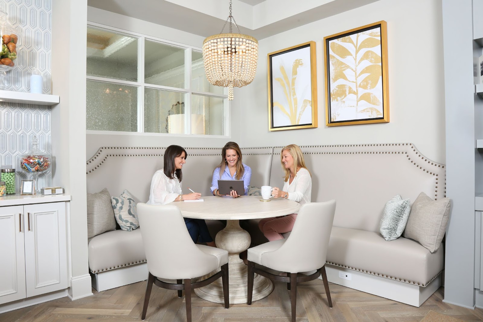 Round table with 3 women sitting around and working. 