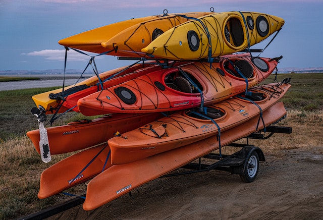 10 kayaks piled up together in a cart for transportation. Kayaks/canoes are an essential kayak camping gear