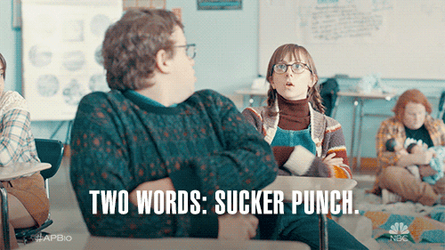 A girl in a classroom pointing her fingers saying, "Two words: Sucker punch."