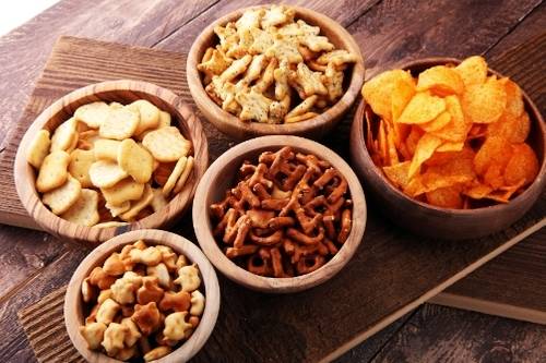 Image of crackers and chips on a wooden background to help describe the chemicals in crackers and chips by The Healthy RD