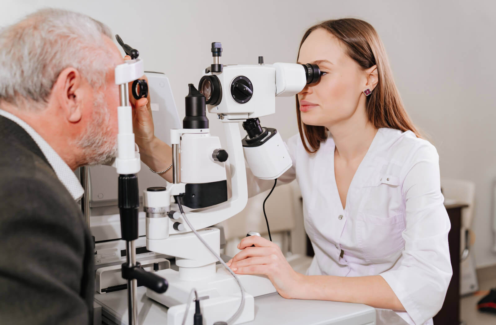 An optometrist performing an eye examination on a senior man using a specialized medical device to check for any eye problems.