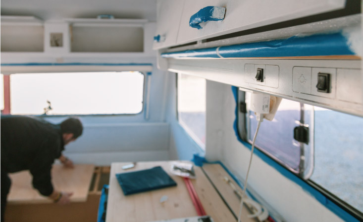 A man is installing bench seating in his camper during a camper renovation.