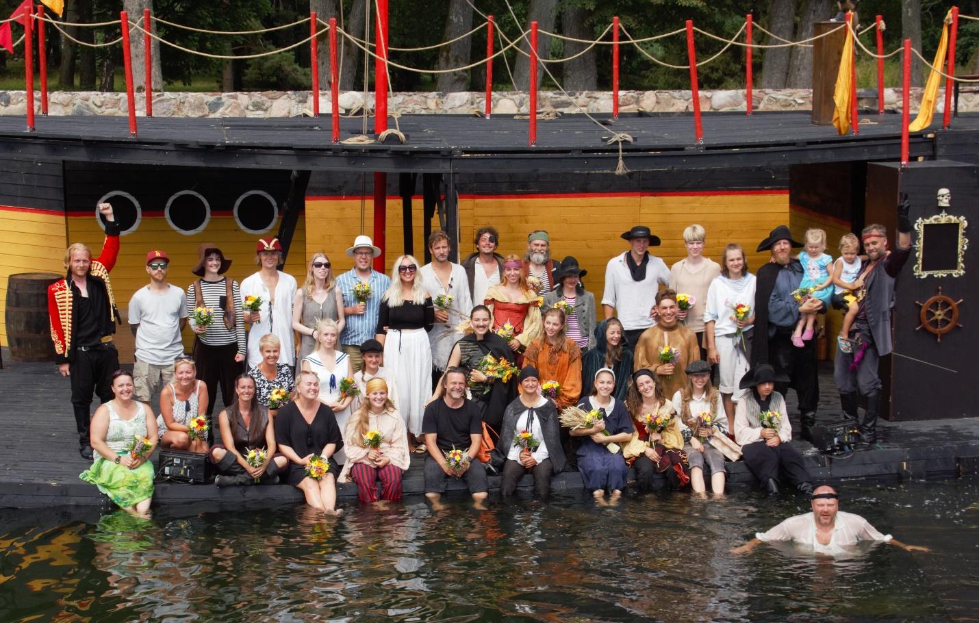 A group of people posing for a photo in a body of waterDescription automatically generated with medium confidence