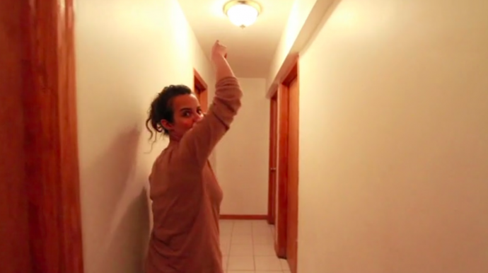 a young woman points to a fake smoke detector in her ceiling