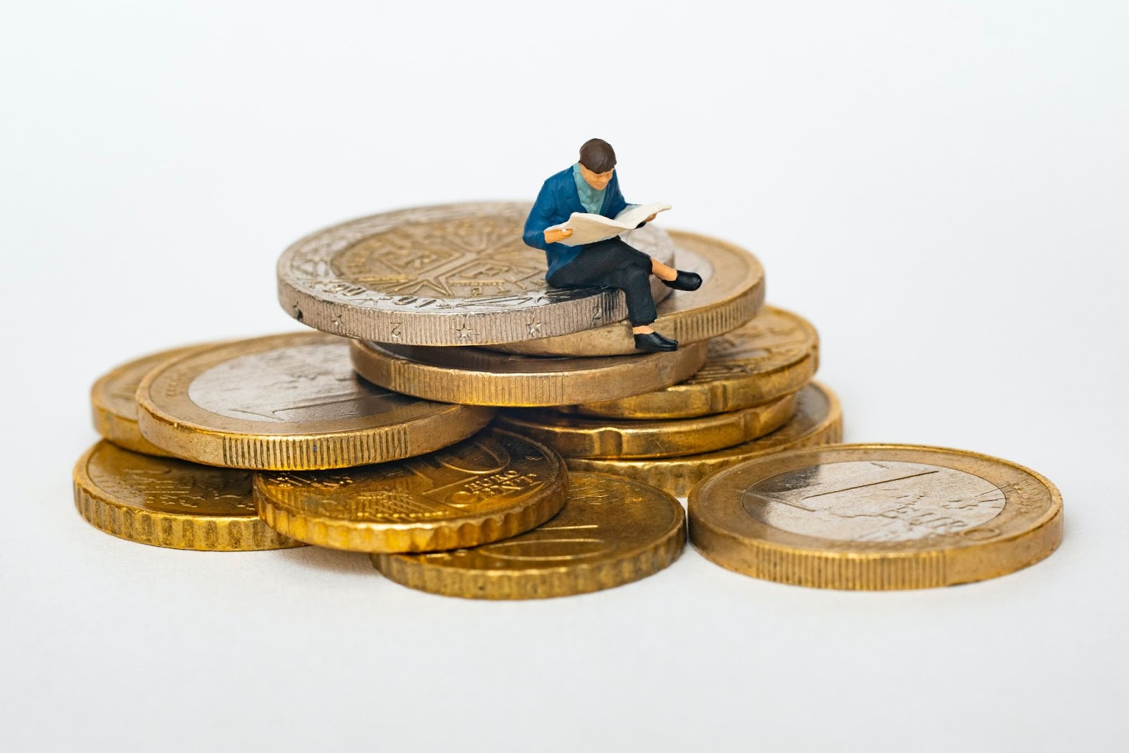 Small figurine reading a paper on a stack of coins