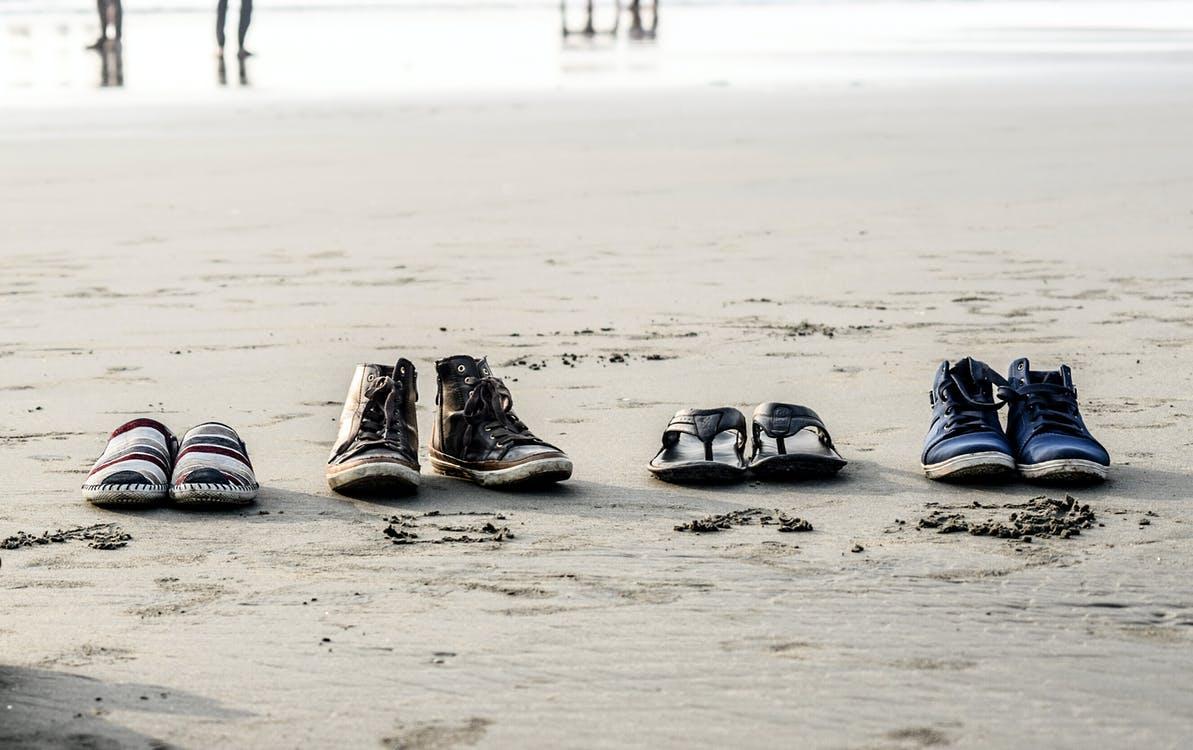 Free Photo of Assorted Pairs of Footwear on Sand Stock Photo