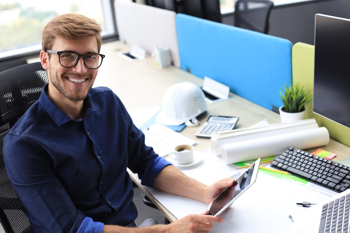 Entrepreneur happily holding a tablet and smiling at the camera