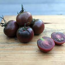 Small pile of cherry tomatoes with one cut open revealing the inner purple flesh.  