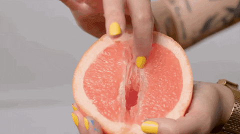 Fingers with yellow nail polish stroke a juicy grapefruit. We hope meditation will get you in the mood.