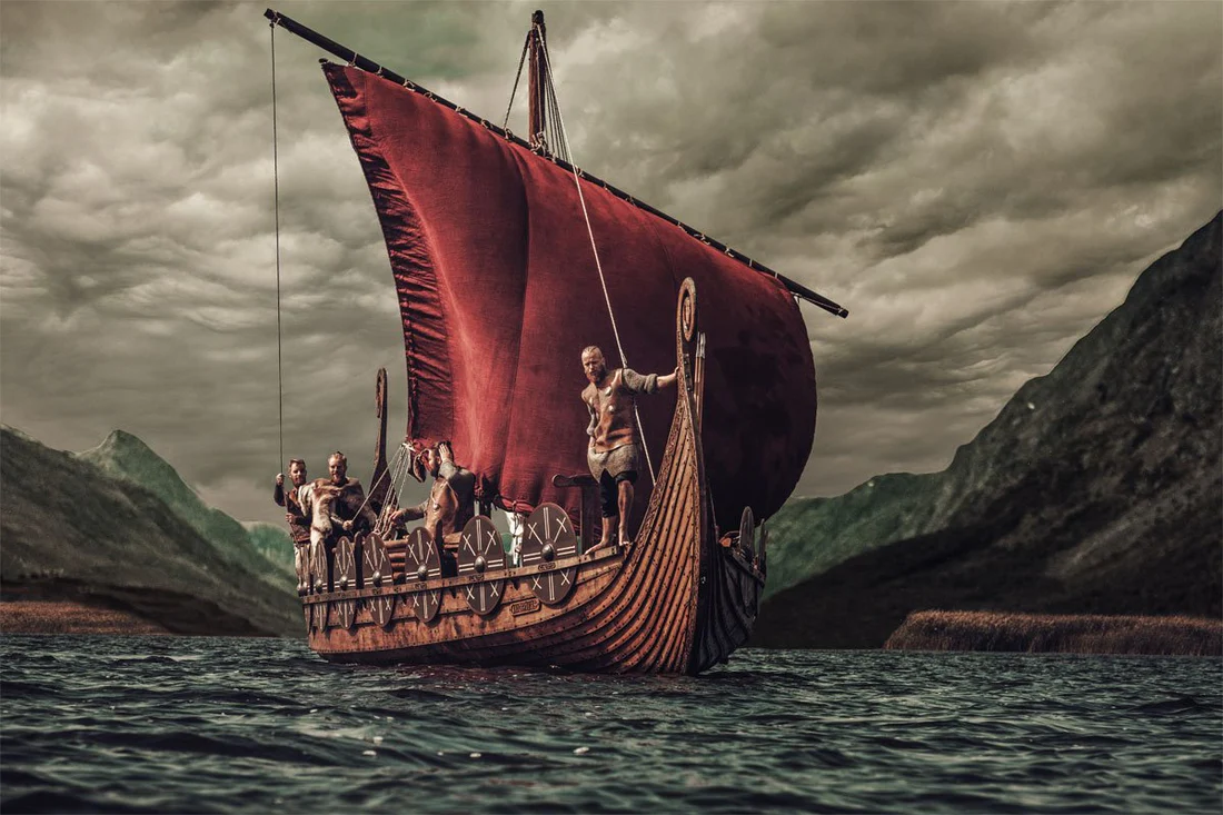 The illustration depicted here showcases the formidable vessel named "Hringhorni" with a striking red sail, while a group of Vikings can be observed aboard the ship. The backdrop of the image reveals a somber sky, adding to the overall mood of the scene.