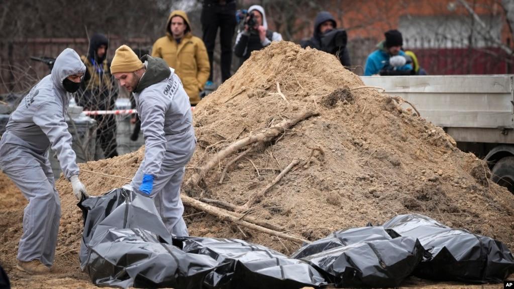 Những người đàn ông mặc đồ bảo hộ khai quật thi thể một số thường dân thiệt mạng trong thời gian Nga chiếm đóng Bucha, ngoại ô Kyiv, Ukraine, ngày 13/4/2022.