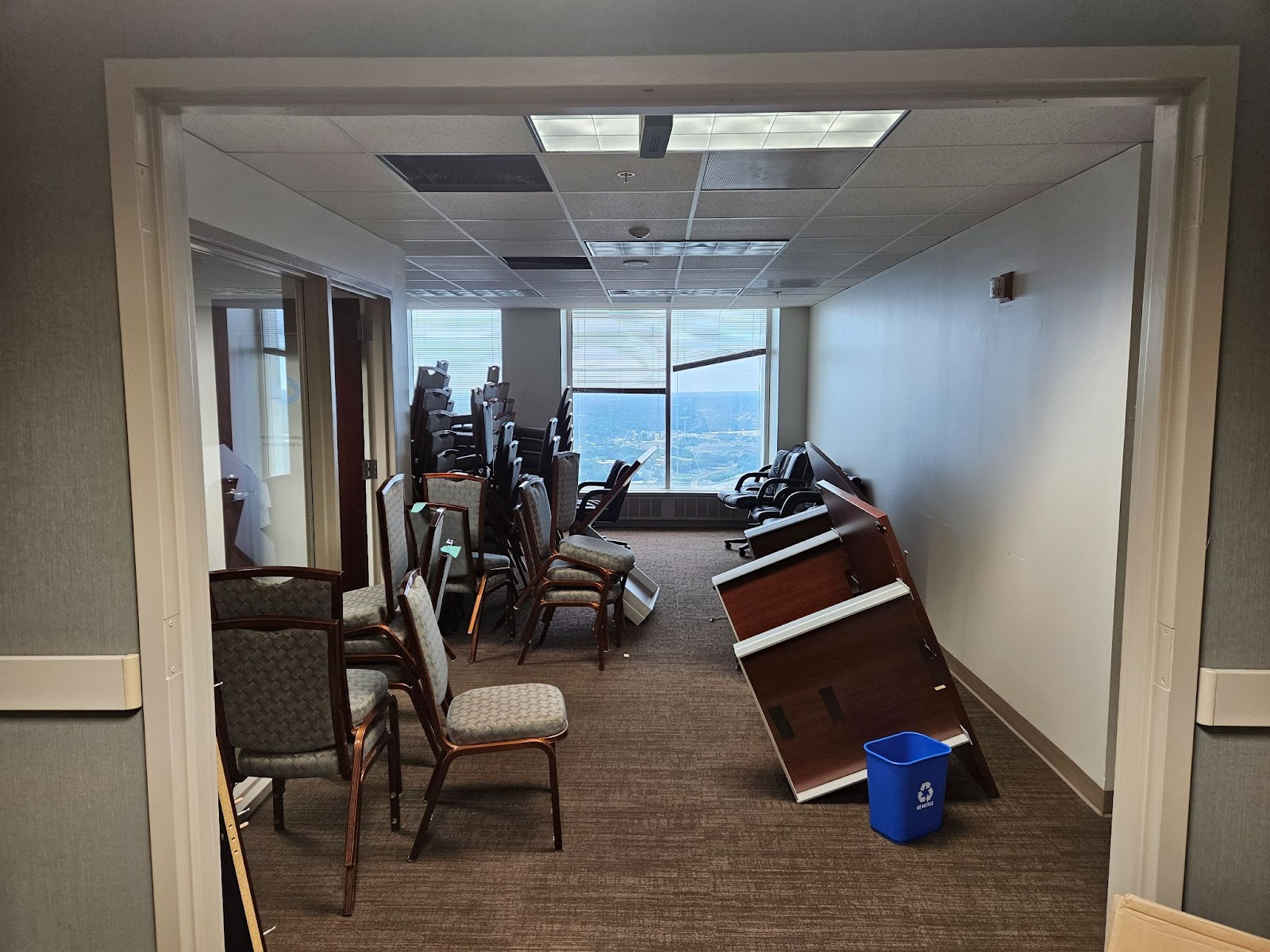 A photo of an office with stacks of unused chairs and other furniture. 