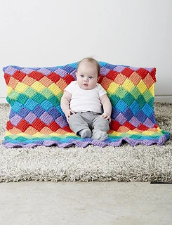 baby sitting up against a tunisian entrelac baby blanket