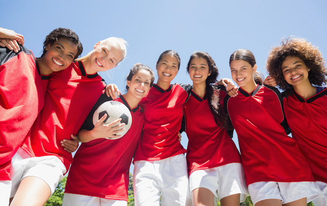 7 female soccer players in red and white uniforms posing for group shot