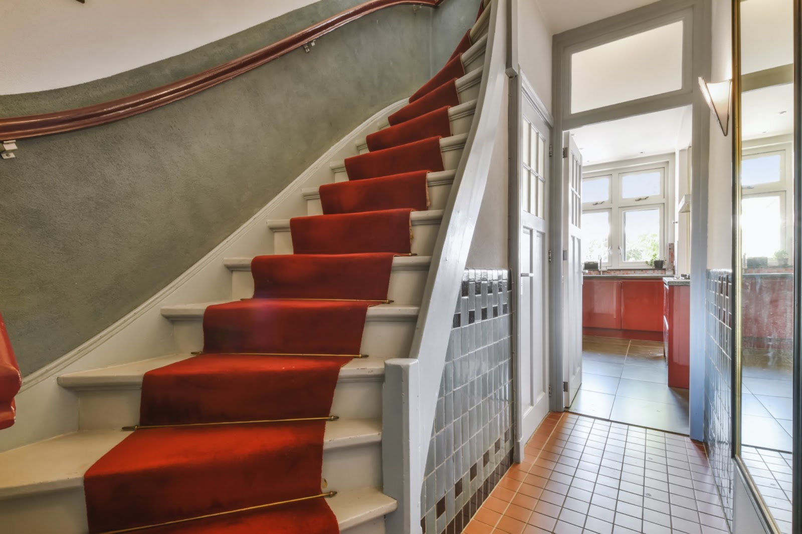 Regal, angular staircase with a dark red stair runner.