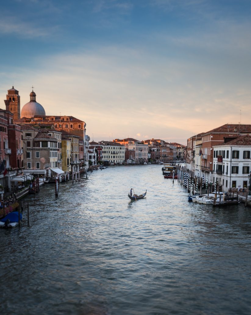 photo of Venice canal with a gondola in the middle and houses lining the sides