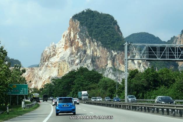 A road with cars and a large rock cliff in the background

Description automatically generated with low confidence