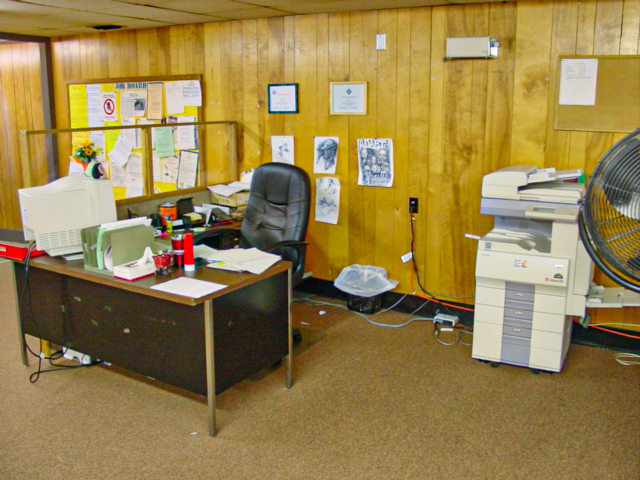 A disheveled desk with copier in the far right of the frame