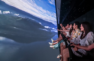 A group of people sitting on chairs looking at a large screen Description automatically generated