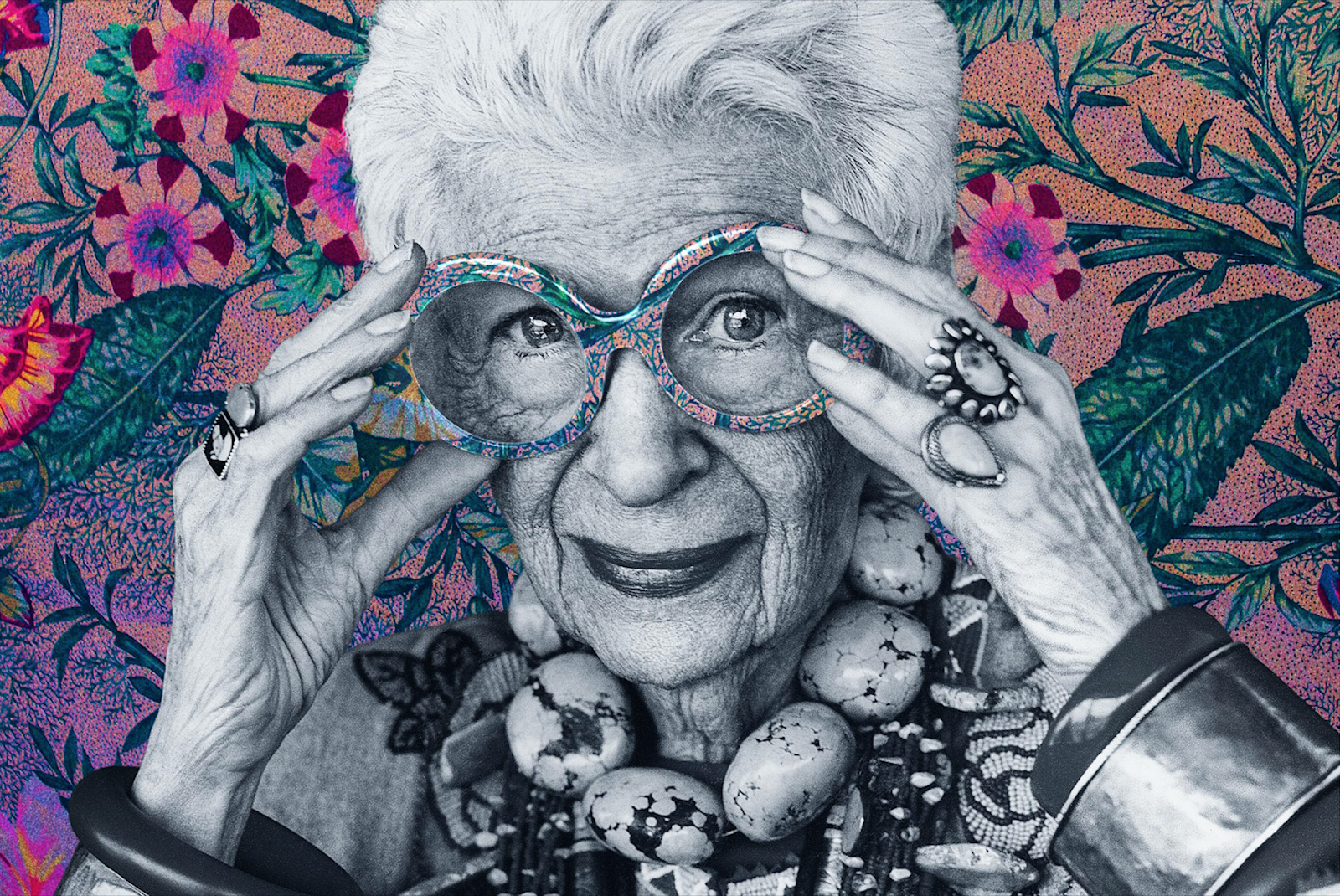 portrait of Iris Apfel in black and white with a colourful, floral background