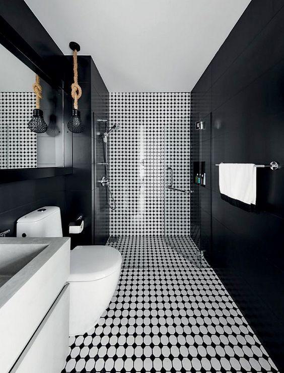 Banheiro com paredes pretas e parede principal com revestimento preto e branco cobrindo parede e piso, louças e armários brancos.