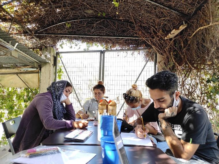 A group of people sitting at a table outsideDescription automatically generated with medium confidence