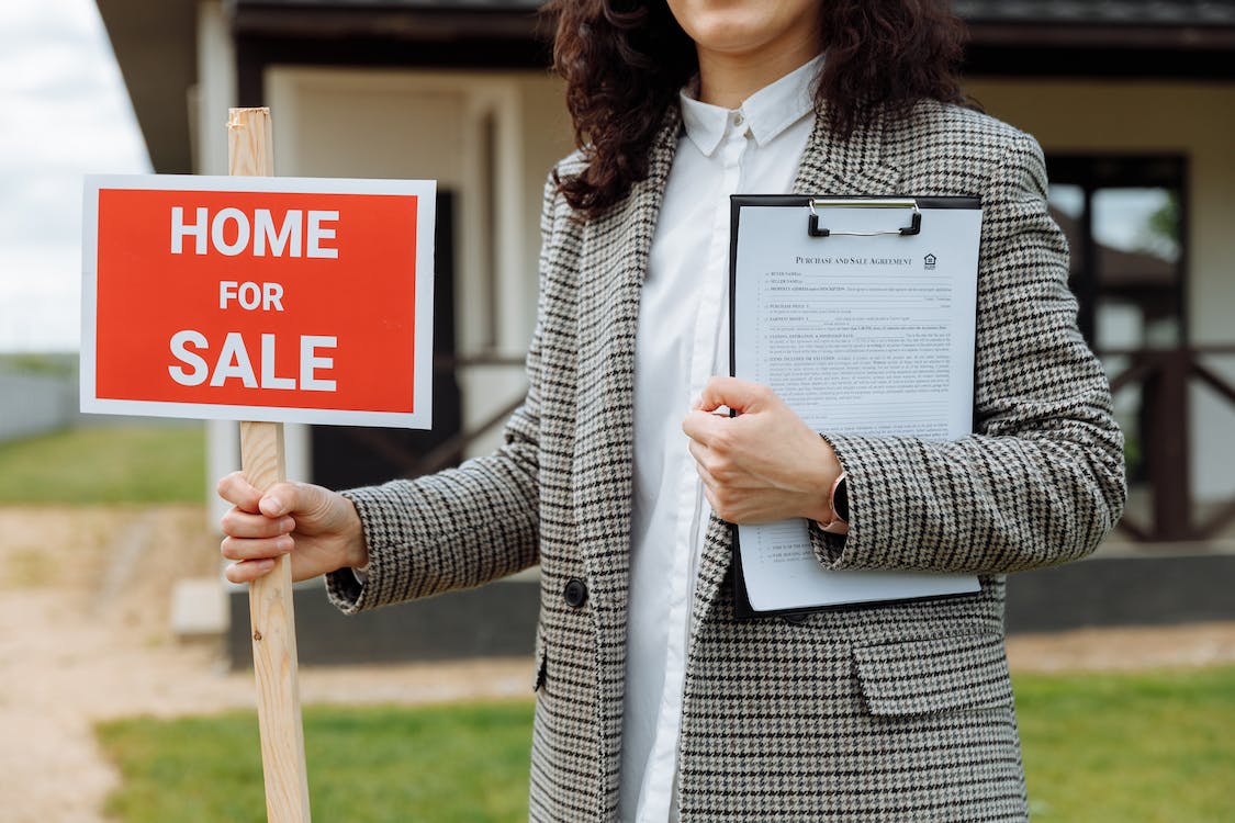 Free Close-up of a Woman Holding a Home For Sale Sign Stock Photo