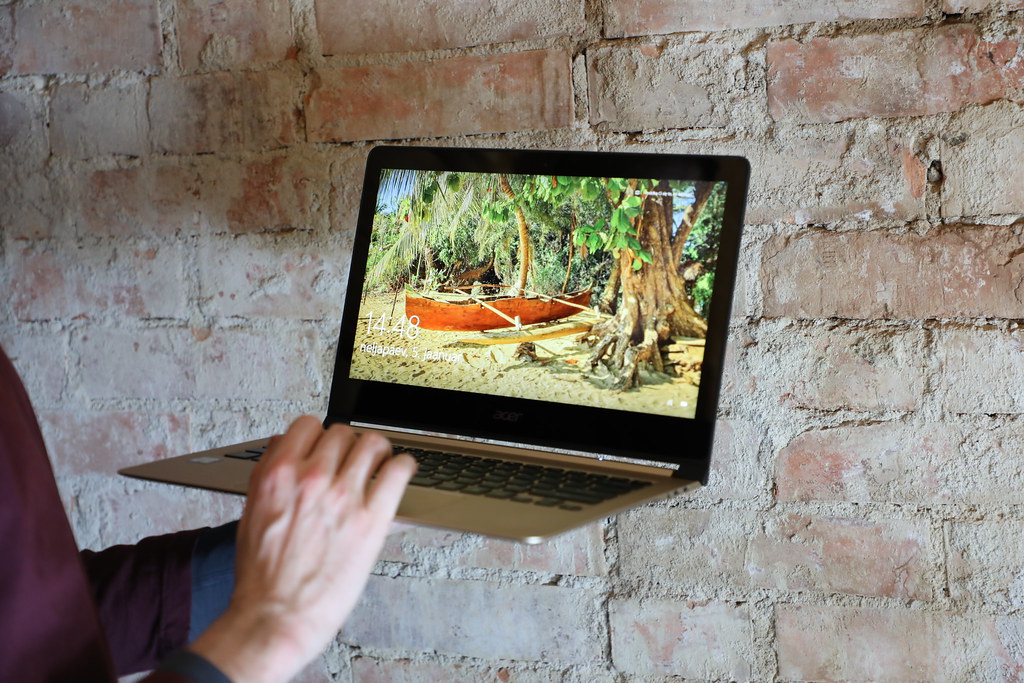 This image shows that acer's laptop is in the hands of man in front of the wall.