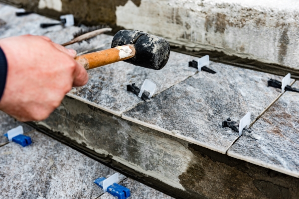 worker-using-hammer-removing-tile-leveling-system-with-plastic-clips-wedges