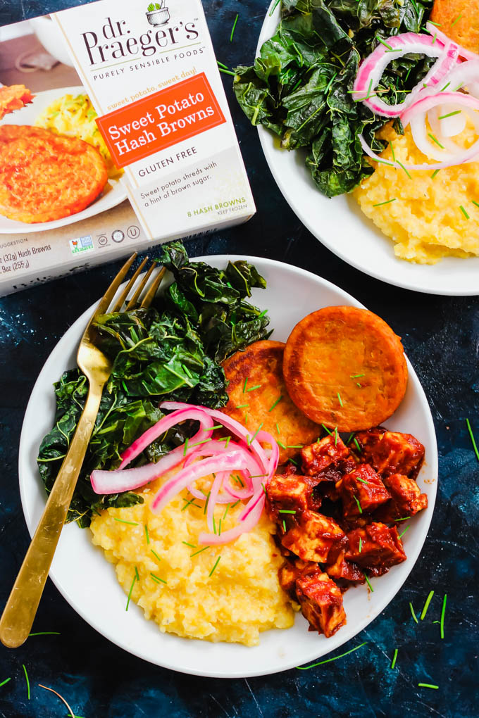 a bowl of tofu, sweet potatoes, greens, grits and pickled onions next to a box of sweet potato hash browns