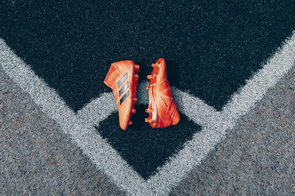 pair of orange adidas cleats on gray surface