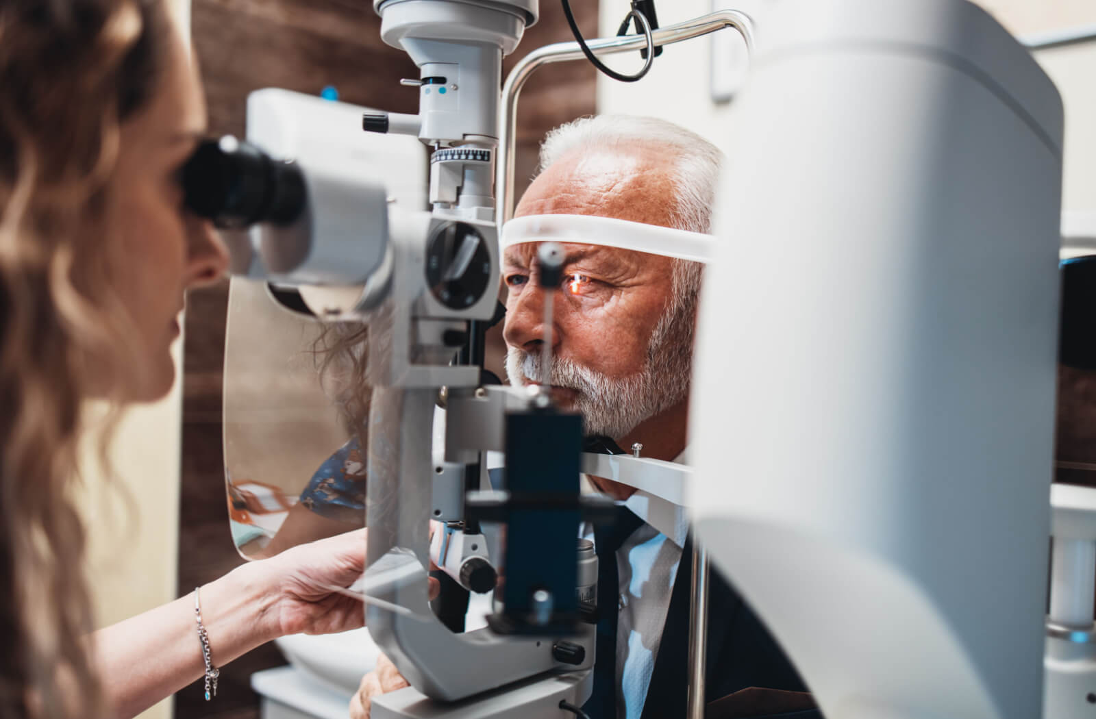 A female optometrist using a medical device to examine the eyes of a senior patient and look for potential eye problems.