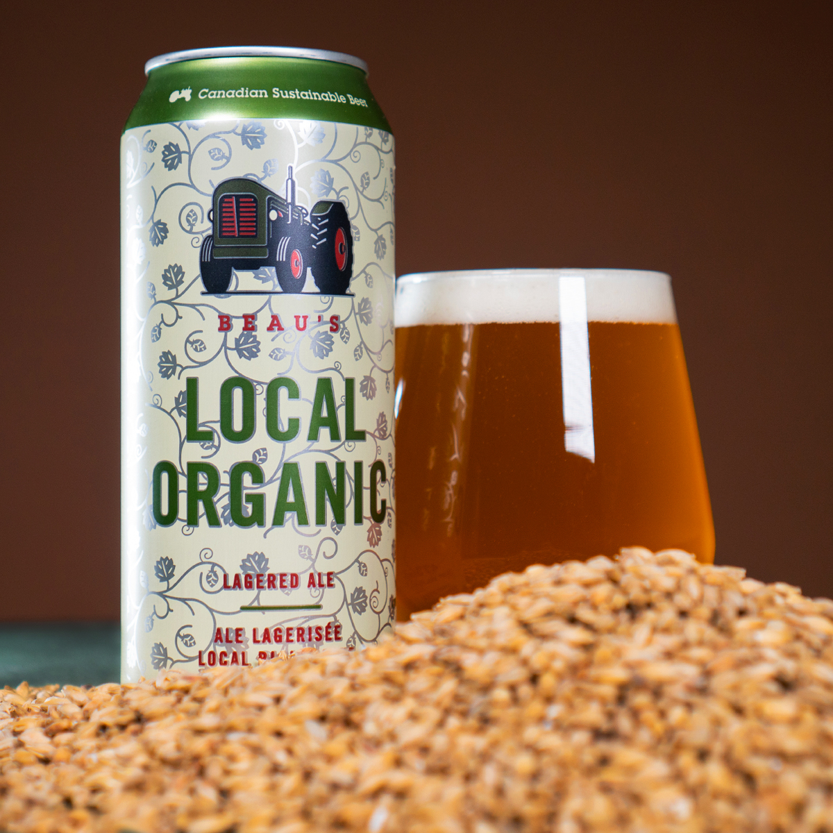 A can of Beau's local organic, beside a glass of the beer with grain in the foreground.