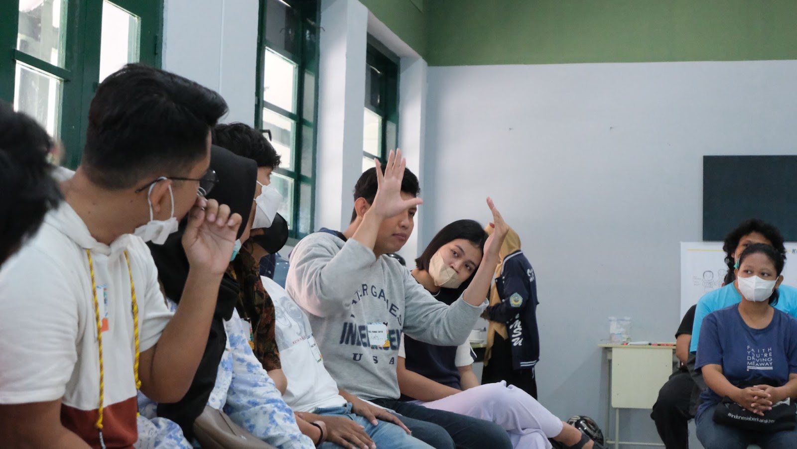 Sekelompok Tuli memerhatikan temannya yang sedang menjelaskan sesuatu dalam Bahasa Isyarat Indonesia atau BISINDO.