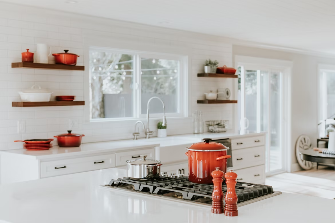 A kitchen with orange and silver pots