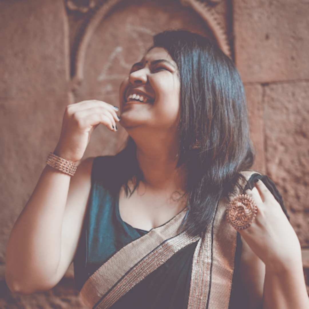 Woman in a black saree with golden borders laughing