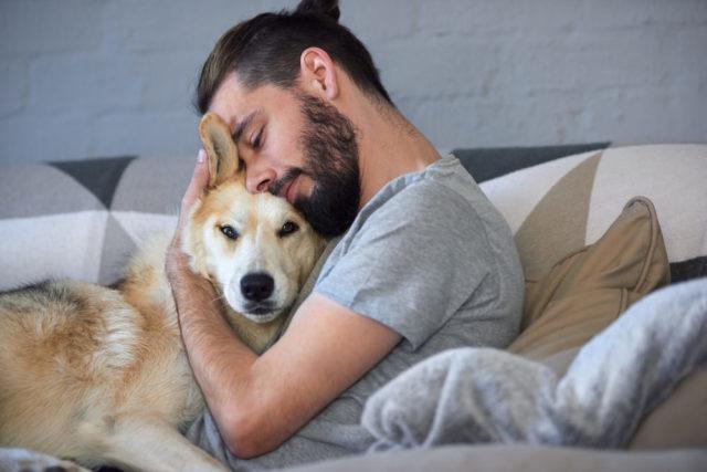 A person and a dog lying on a bed

Description automatically generated