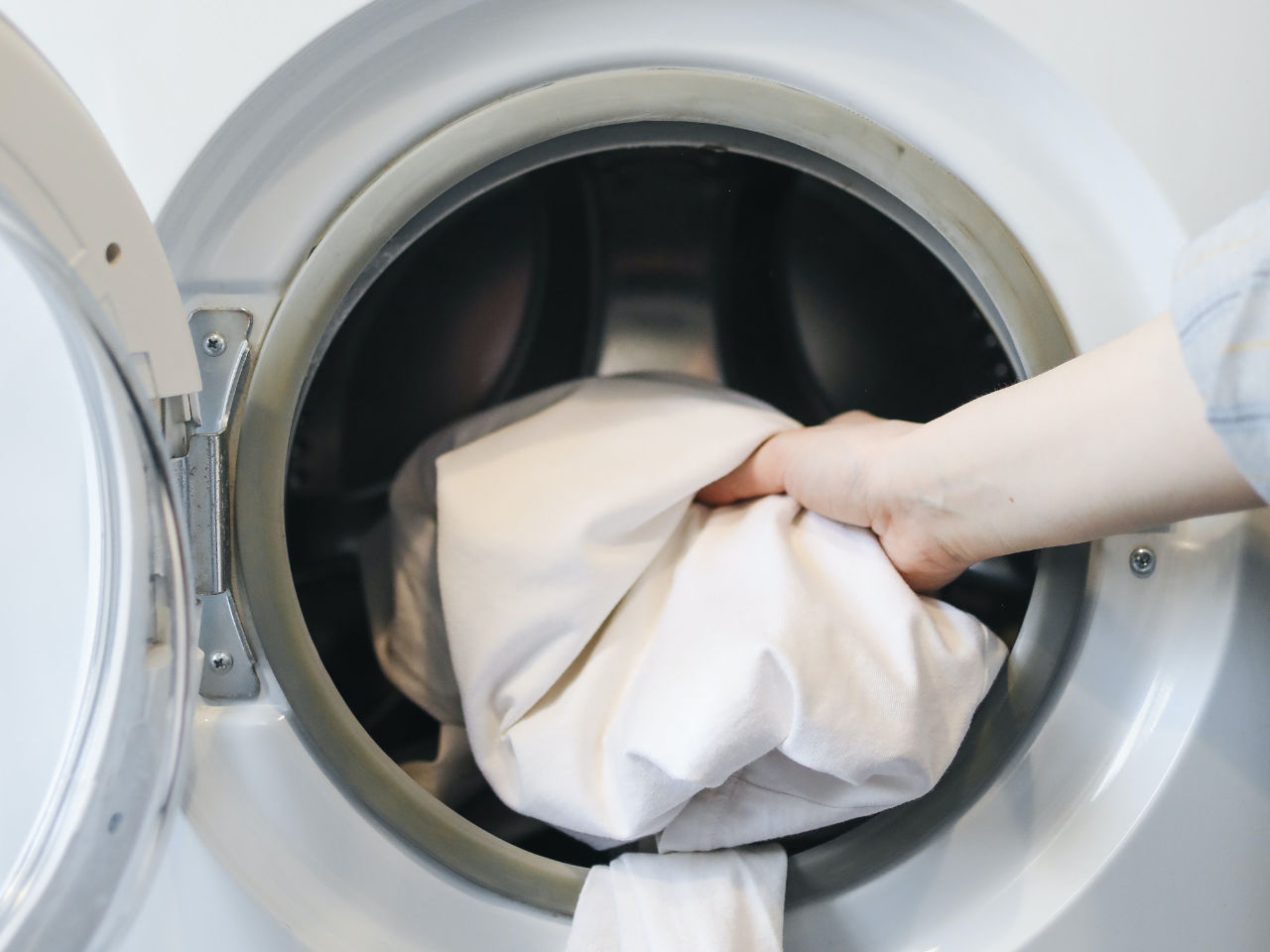 Person putting a linen on washing machine.