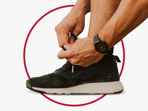 Sporty man with black watch tying shoe