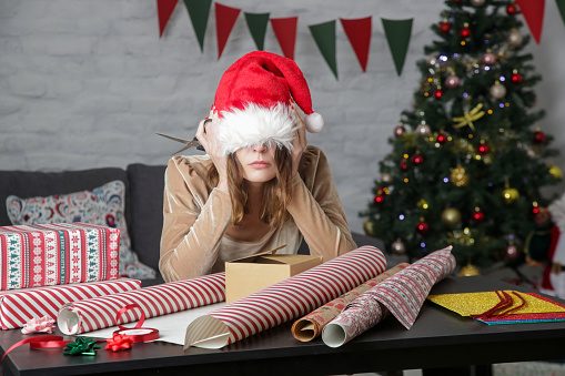 Depressed frustrated woman wrapping Christmas gift boxes, winter holiday stress concept.  Anxiety treatment in Woodland Hills, CA can help with coping skills by talking to an anxiety therapist.  91364 | 91307 | 91356 | 91301 | 91302 | 91372 | 91367