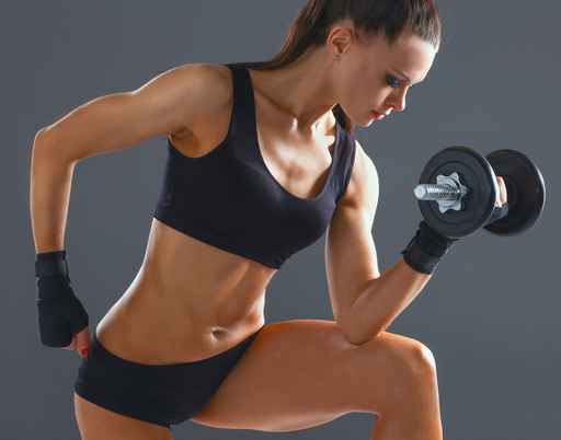 Athletic woman pumping up muscules with dumbbells
