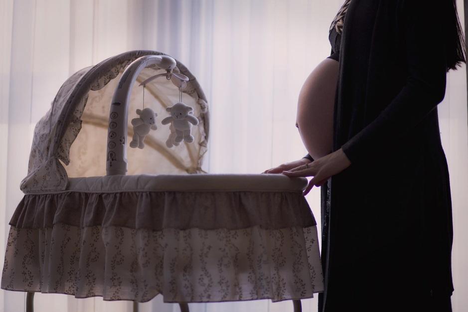 pregnant mom touching a baby crib