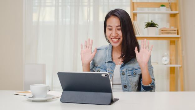 Freelance business women casual wear using tablet working call video conference with customer in workplace in living room at home. happy young asian girl relax sitting on desk do job in internet. Free Photo