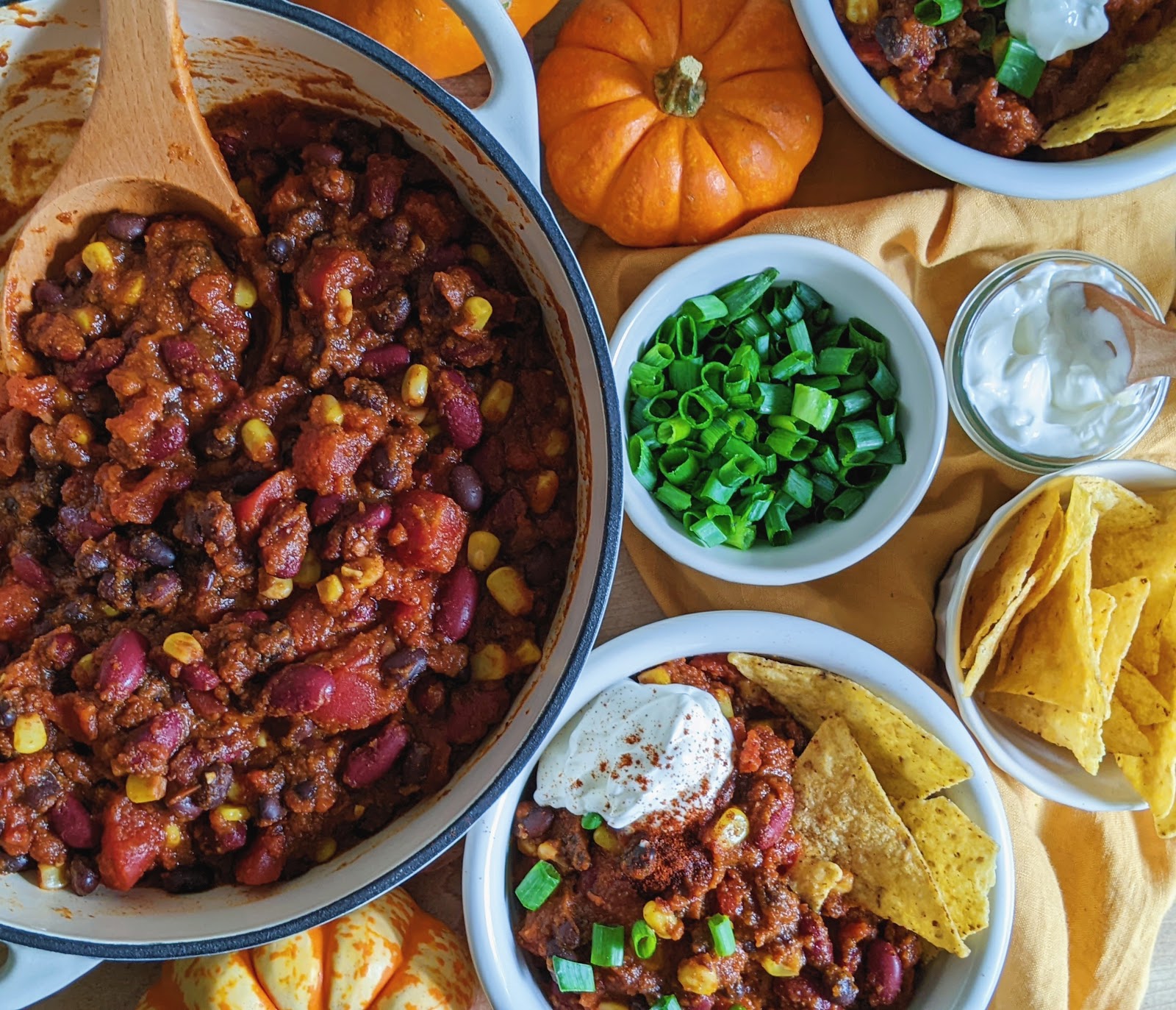 top down view of pumpkin turkey chili in bowls with tortilla chips and garnishes