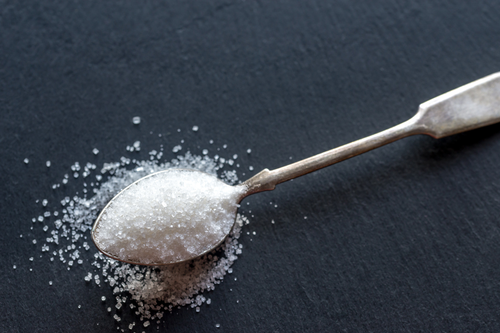 A Teaspoon of White Sugar on a Dark Background