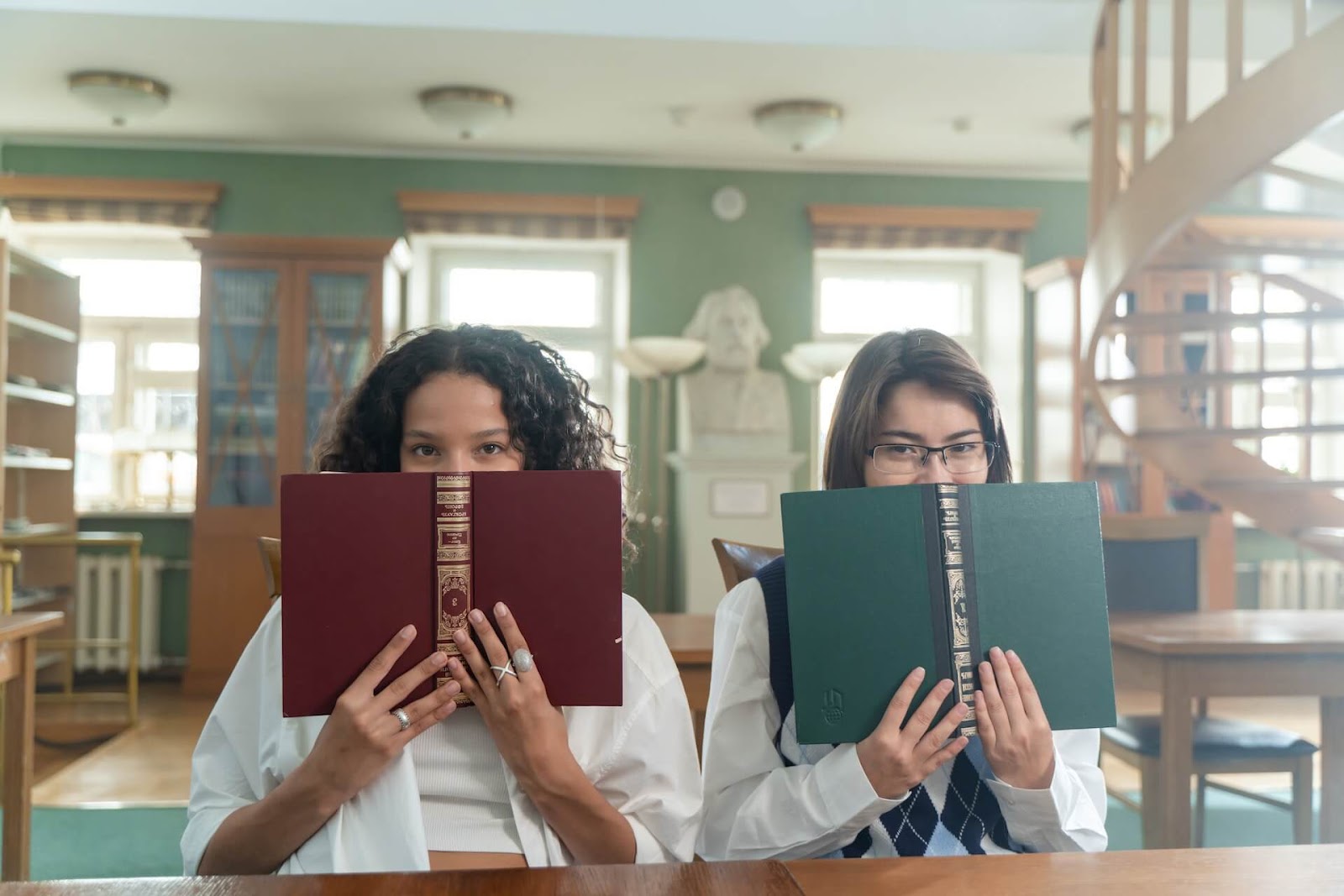 Two students holding books in the library
