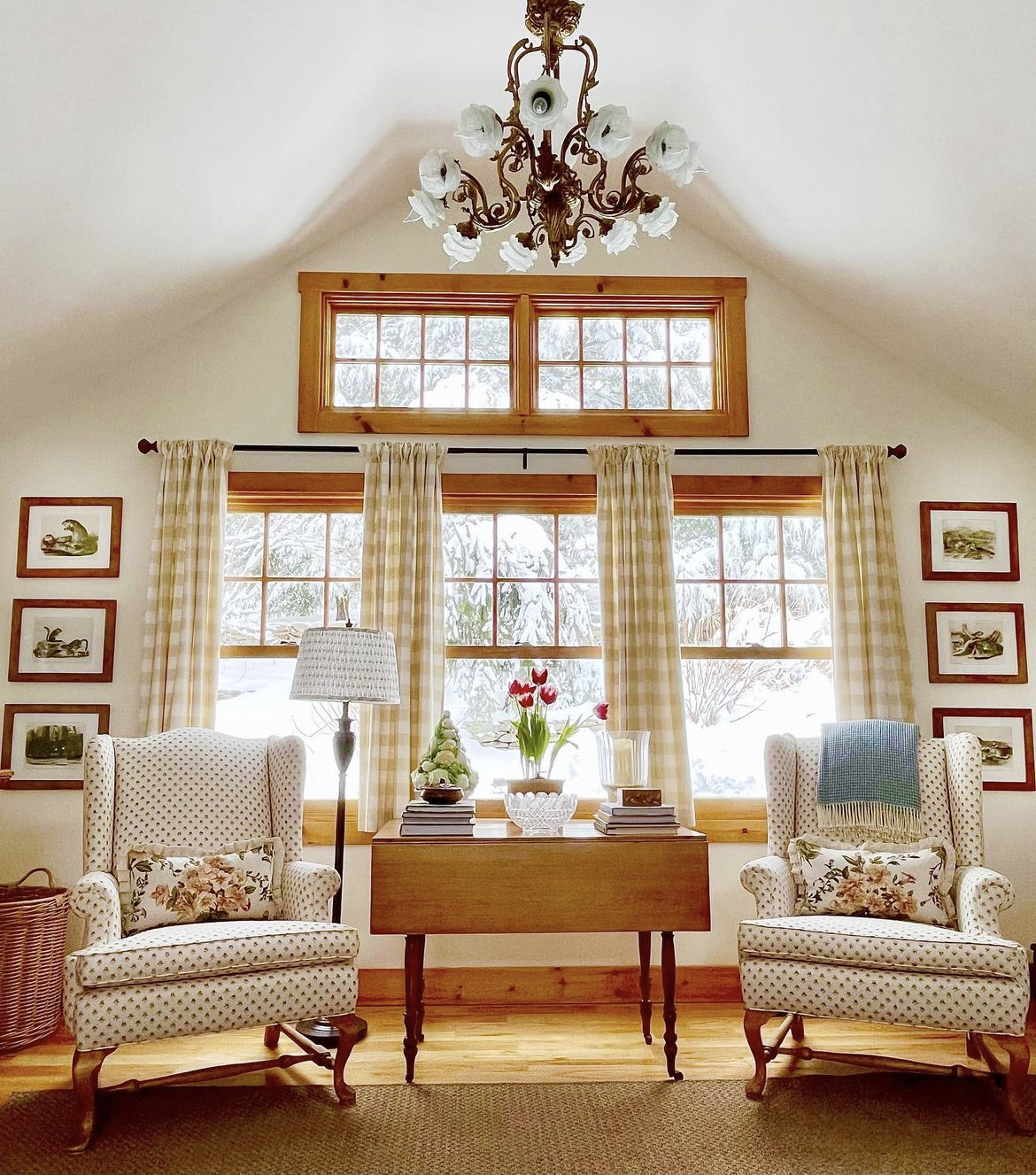 This part of the cottage living room is cozy and inviting, with a warm and rustic atmosphere that makes you feel right at home. The room is filled with natural light, thanks to the large windows. The walls are painted in a soft cream color, which adds to the room's charm and character.There are two comfortable armchairs, upholstered in a soft and cozy fabric that invites you to curl up and read a book. The armchairs are placed next to a small side table, which is perfect for placing a cup of tea or a book.The side table is made of wood, and it has a natural look that complements the rest of the room's décor. On top of the table, there is a small vase of freshly picked flowers, which adds a touch of color and freshness to the room.