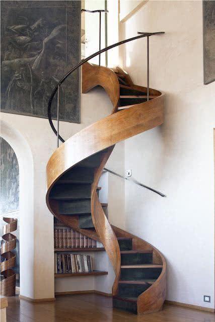 Escada em formato caracol com revestimento de madeira e corrimão e ferro