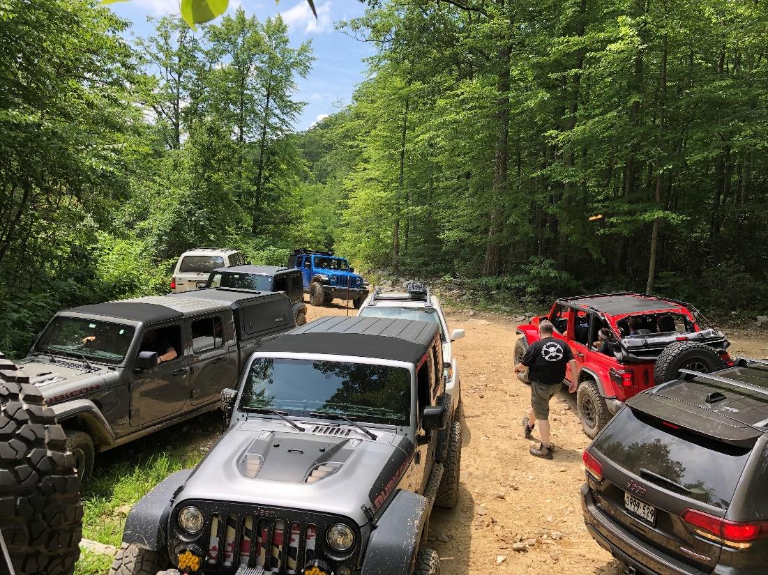 A group of jeeps parked on a dirt road

Description automatically generated